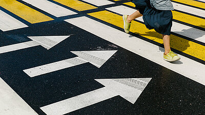 Ein genetisches Tumorprofil kann ein Wegweiser sein Eine Frau bewegt sich über eine Straße mit Richtungsvorgabe