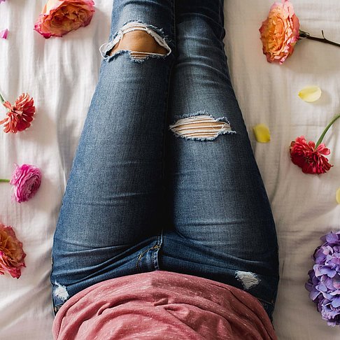 Eine Frau liegt auf dem Bett umringt von Blumen