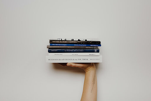 Hand stemmt sechs Bücher in die Höhe