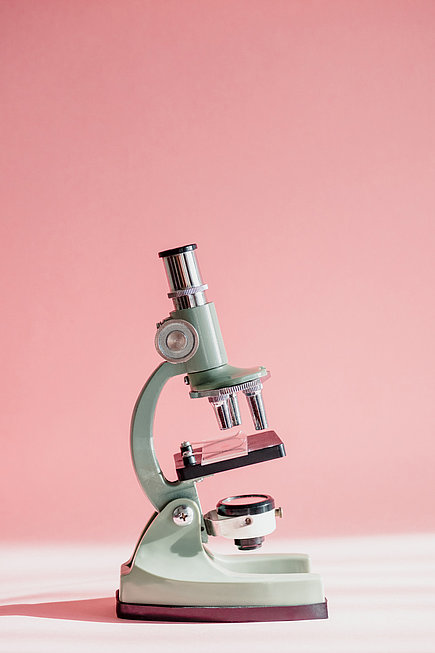 Weißes Mikroskop vor rosa Hintergrund